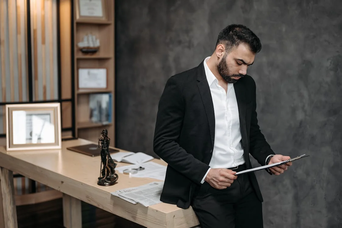 man in black suit reading a document