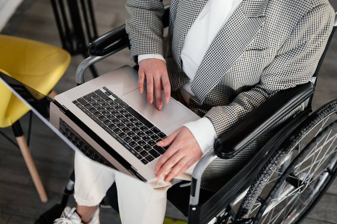 person in wheelchair using laptop computer