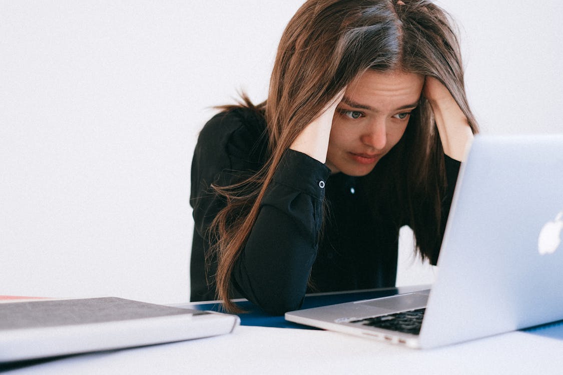 stressed woman looking at laptop with hands on head