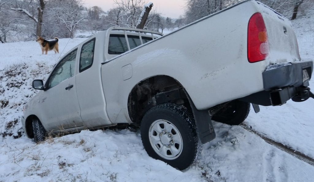 white pickup truck stuck in ditch following auto accident