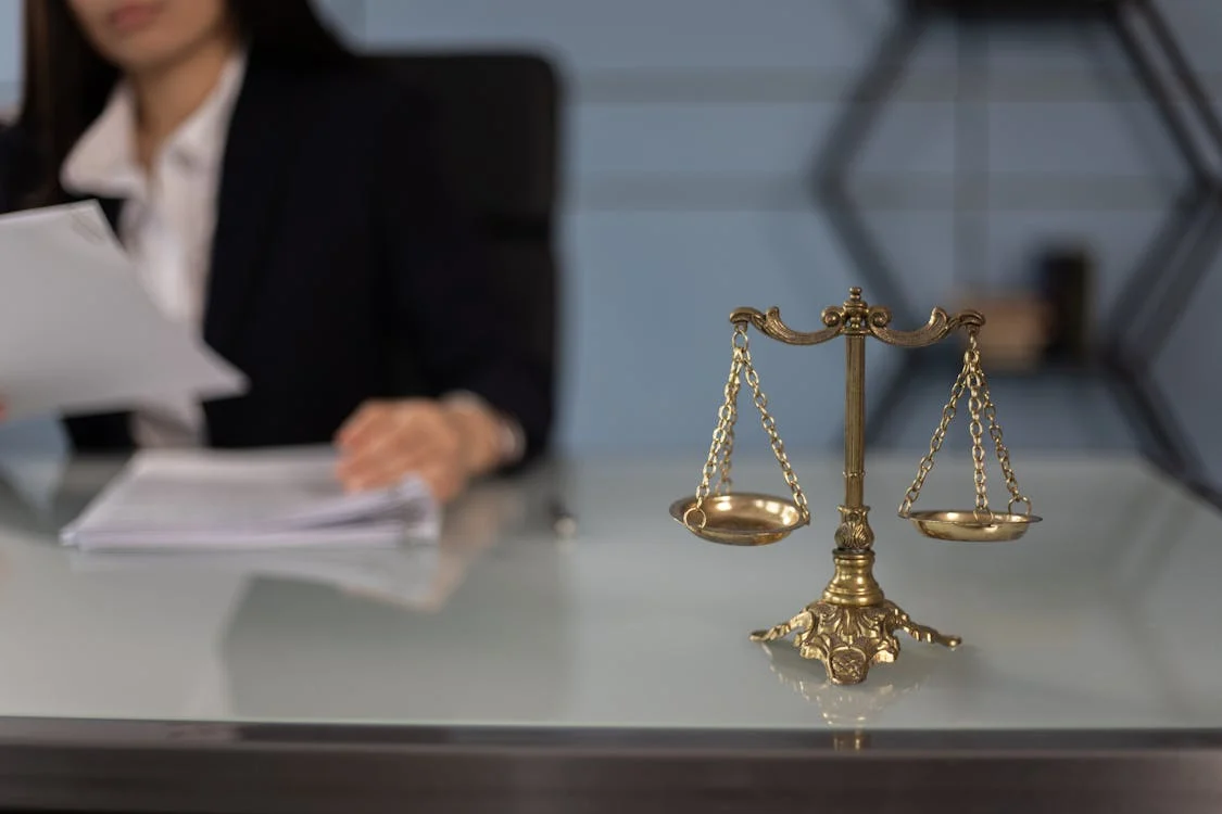 scales of justice in foreground, lawyer reviewing documents in background