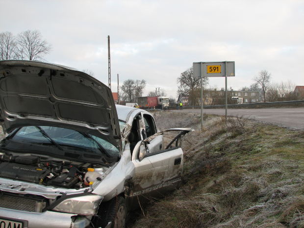A crashed car in a ditch beside a road