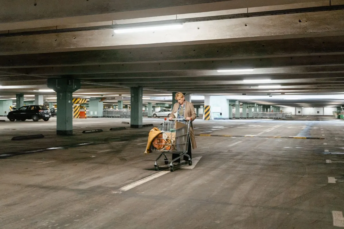 An old woman pushing her cart in a parking lot
