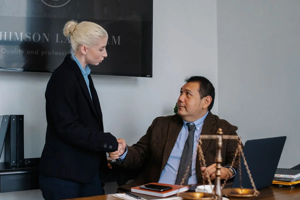 Two people shaking hands behind a desk