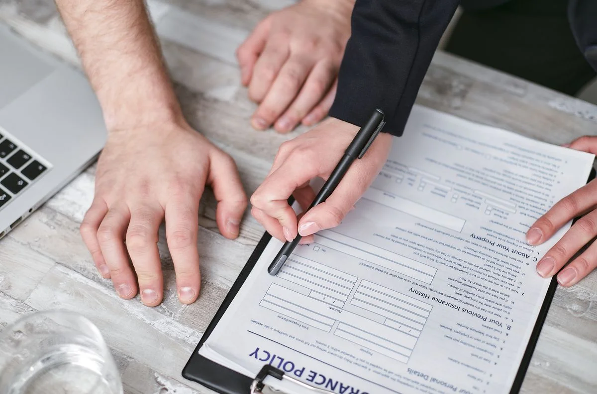 insurance-policy-document-review A person holding a black pen pointing on a document that reads insurance policy