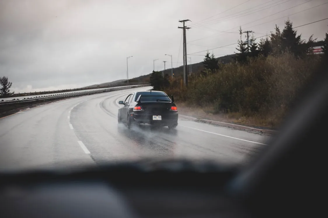 Car driving around a curve on a wet road in rainy weather